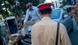 Tài xế vi phạm cố tình ngồi lên nắp capô phản đối cảnh sát cẩu xe