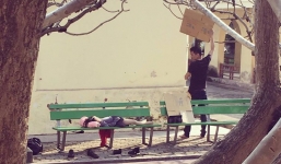 Ông bố dùng tấm bìa các-tông che cho con nằm ghế đá ở bệnh viện