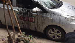 Taxi đậu trước cửa hàng sửa chữa xe máy bị hắt dầu luyn khắp thân xe