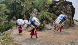 Xúc động câu chuyện phía sau bức ảnh phụ nữ vùng cao còng lưng cõng bồn nước lên bản