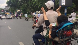 Bé trai nằm gác chân lên vai bố vắt vẻo lượn đường phố gây tranh cãi