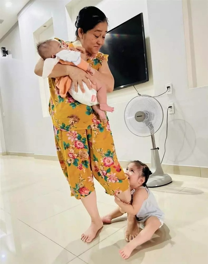 Cô bé ôm cả chân bà khi bà bế em