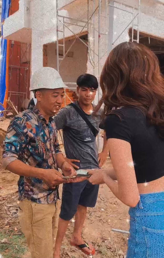 Ngọc Trinh hào phóng cầm cả xấp tiền đi phân phát cho những người thợ xây đang làm việc tại căn biệt thự cho Vũ Khắc Tiệp. Ảnh cắt từ clip