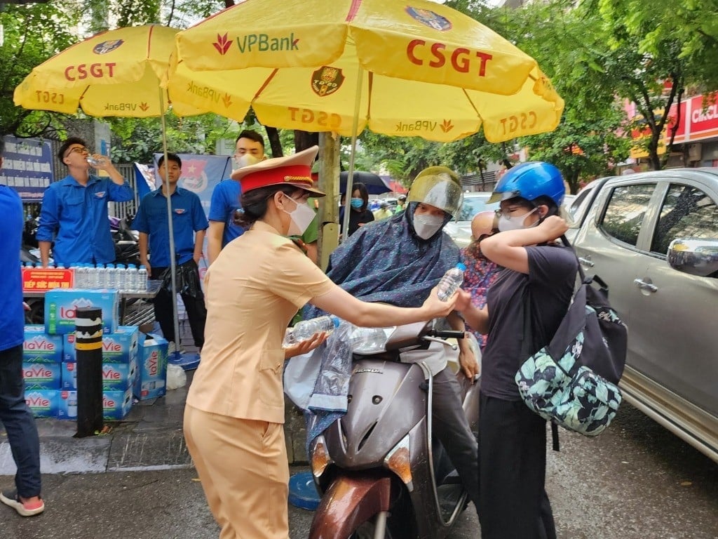 Đội CSGT số 6, Hà Nội, cùng Công an phường Mai Dịch, quận Cầu Giấy đảm bảo trật tự ATGT, phát nước miễn phí cho các thí sinh tại điểm thi trường THCS Mai Dịch. Ảnh: PLXH