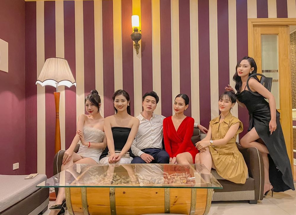 Trong Lân (ngồi giữa, áo trắng) đăng ảnh với gương mặt toát lên sự 'đểu cáng' khi ngồi cùng các diễn viên nữ trong phân cảnh ở quán rươu. Ảnh: FB Trọng Lân.