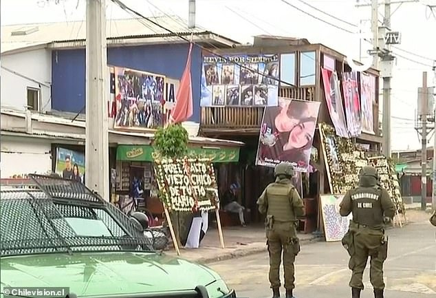 Các sĩ quan cảnh sát Chile được nhìn thấy đứng trước nhà của Carlos Parra, một kẻ buôn ma túy 22 tuổi bị sát hại ngày 22/11. Gia đình để tang cái chết của anh ta trong 5 ngày bằng cách tổ chức tiệc, đốt pháo hoa và phát sóng trực tiếp lễ tang trên mạng.