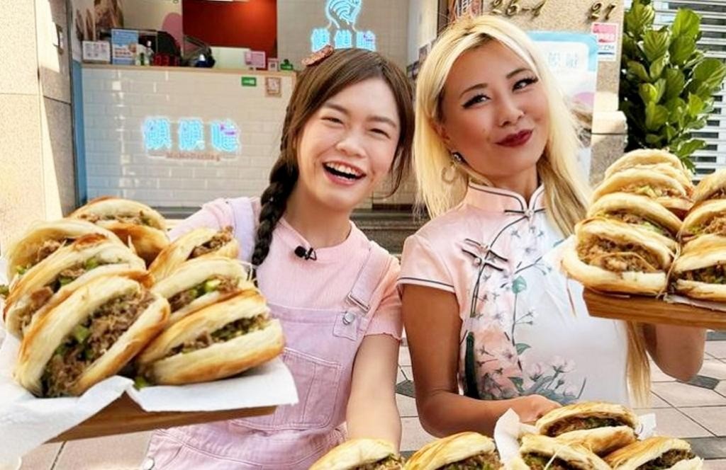 Huang (phải) và một người bạn đang cầm những chiếc bánh mì kẹp thịt.