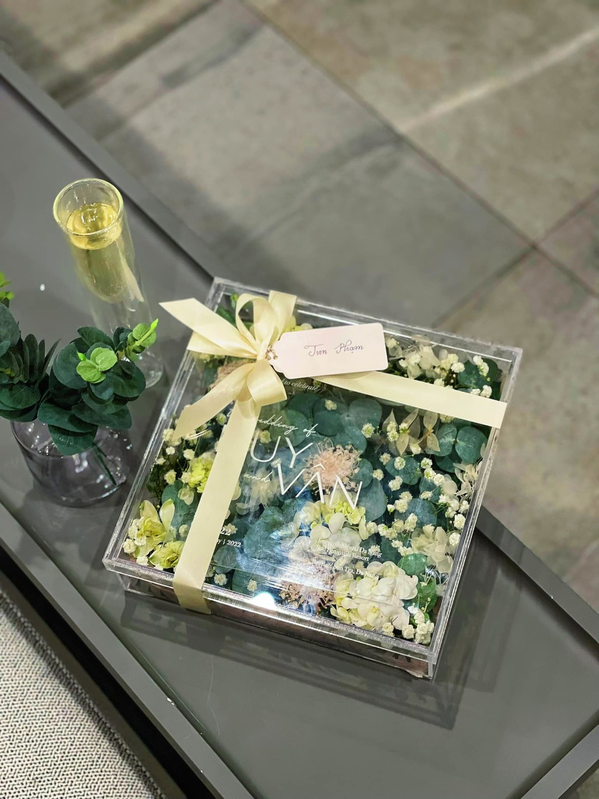 Bên ngoài hộp để thiệp cưới là ruy băng cột nơ tinh tế, đính kèm một chiếc thẻ viết tay tên khách mời. Bên trong để hoa tươi được vận chuyển trong ngày.