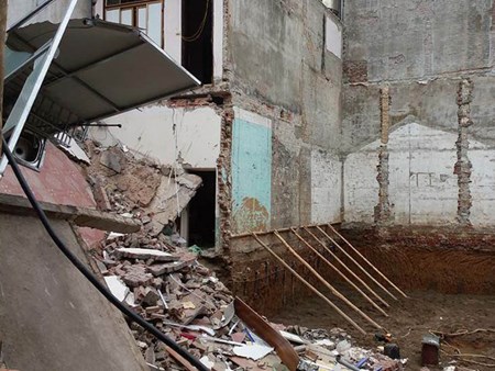 Công trình mới lúc thi công còn gia cố bằng cách đóng một hàng cọc sát tường nhà bên cạnh, nhưng vẫn không chịu nổi. Ảnh: FB