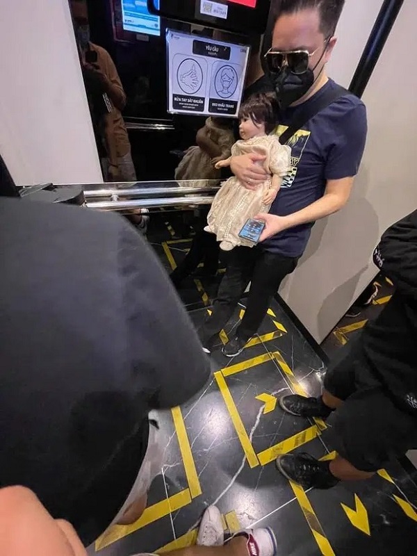 Victor Vũ bế búp bê đi quanh chung cư, đặt chễm chệ bên ghế khi ngồi cà phê.