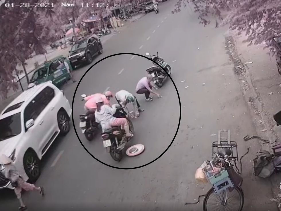 Người đàn ông mặc áo đỏ không xuống xe nhưng cúi xuống để lượm tiền, lúc này một người đàn ông mặc áo tím cũng xuất hiện tham gia nhặt tiền