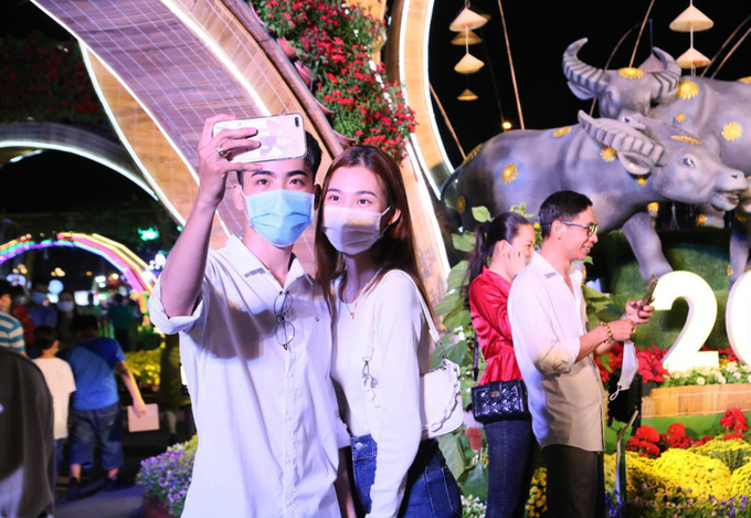 Người dân tại TP Cần Thơ chụp ảnh tại đường hoa trước khi đóng cửa. UBND TP Cần Thơ quyết định dừng hoạt động đường hoa vào lúc 22h cùng ngày, sớm hơn 5 ngày so với kế hoạch. Việc làm này nhằm hạn chế tập trung đông người, phòng chống Covid-19. Ảnh: VNE