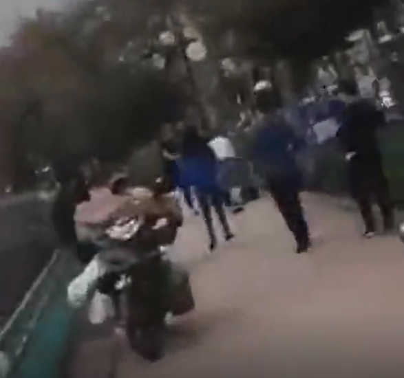 Người phụ nữ áo xanh được cho là vợ đang chạy đến ngăn cản chồng đánh nhân tình. Ảnh chụp từ clip