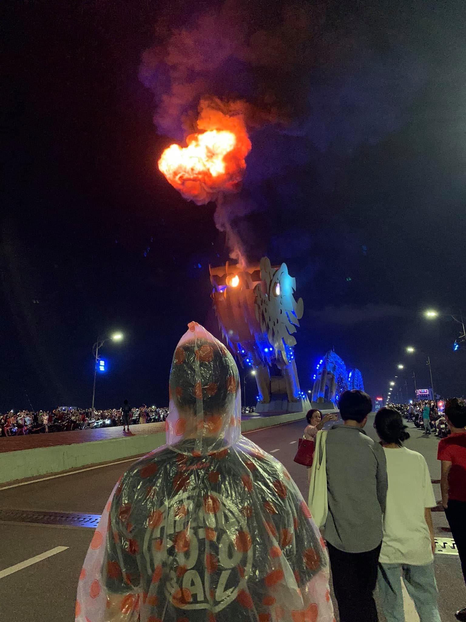 Chàng thanh niên mặc áo mua đứng giữa cầu Rồng nhận phải nhiều cái nhìn dè bỉu từ những người xung quanh. Ảnh: MXH