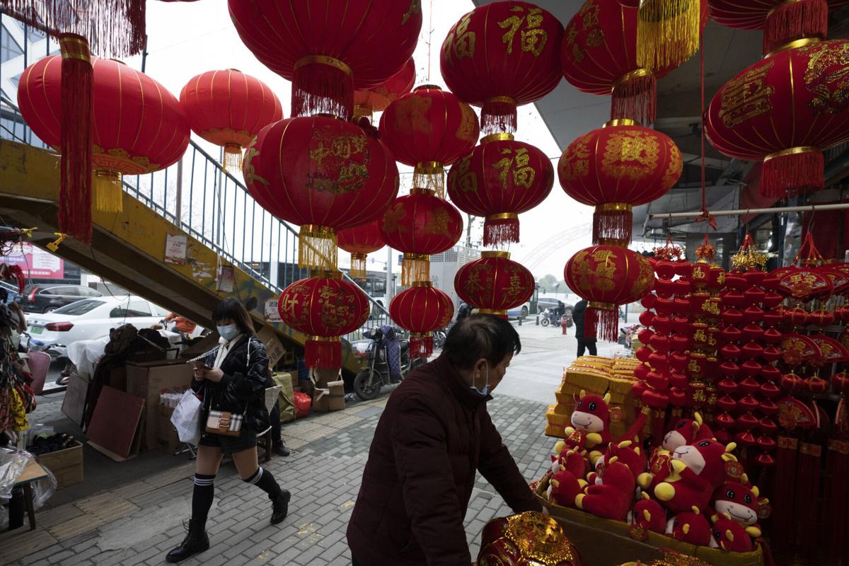 Một người dân đeo khẩu trang đi qua cửa hàng bán đồ trang trí Tết Nguyên đán tại Vũ Hán. Ảnh: AP