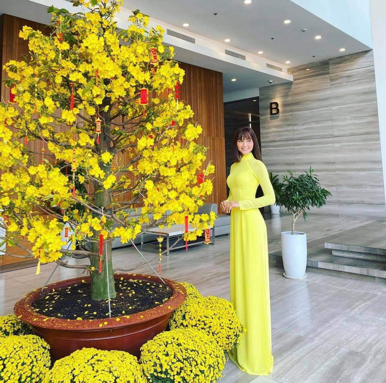 Nàng hậu H'Hen Niê năm nay diện chiếc áo dài màu vàng rực rỡ, đứng khoe dáng bên chậu mai và cúc vàng. Cứ mỗi lần Tết đến là H'Hen Niê lại lo lắng cho vòng 2 của mình. Năm nay cô nàng ' Mùng 1 tranh thủ mặc áo dài trước rồi nhập tiệc đón bé mỡ về'. Ảnh: Instagram