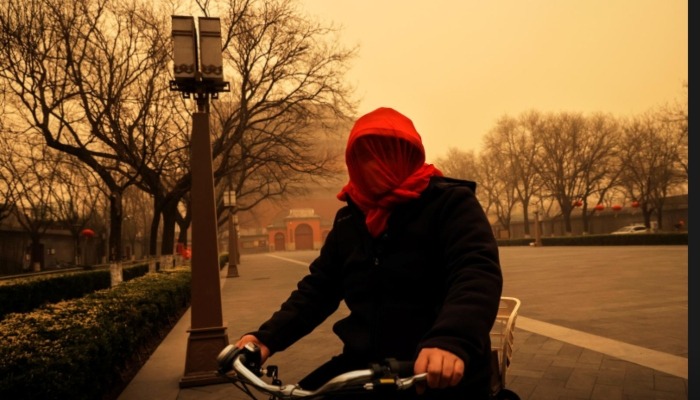 Một phụ nữ đi xe đạp trùm kín đầu trong giờ cao điểm sáng nay. Ảnh: Reuters