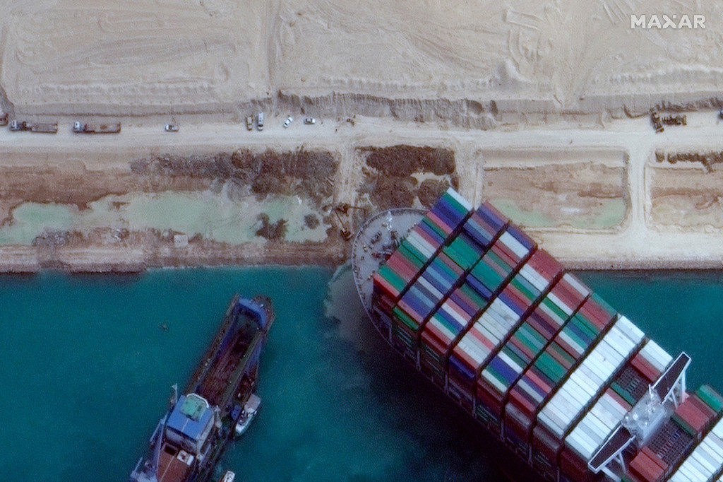 Tàu kéo và máy đào tiếp tục đẩy và kéo tàu container Ever Given trong khi nó còn mắc kẹt. Ảnh: AP