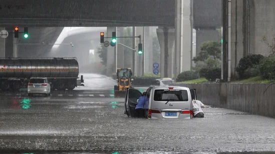 Mọi người đẩy một chiếc xe qua dòng lũ dọc con phố sau trận mưa lớn. Ảnh: AP
