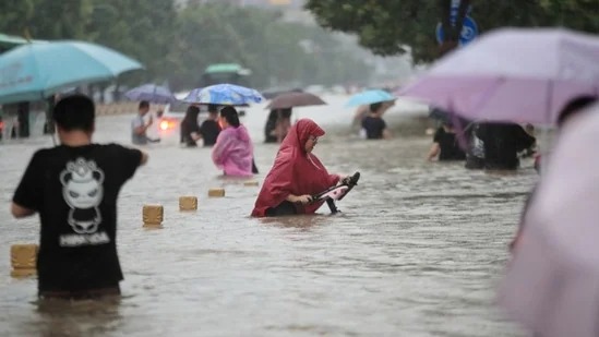 Người dân lội qua dòng nước lũ trên con đường ngập lụt tại Trịnh Châu. Ảnh: Reuters