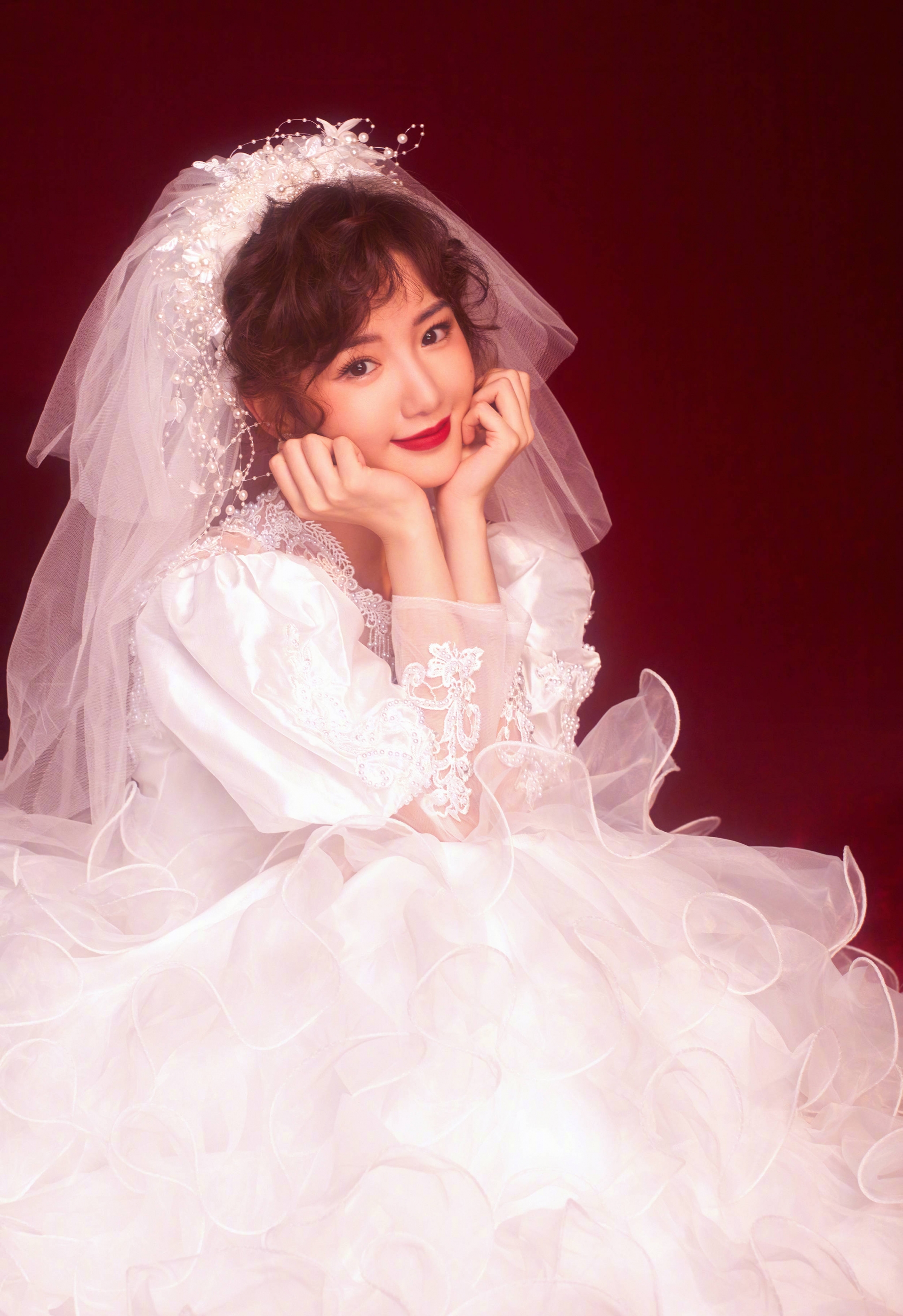 Hai tay chống cằm, tạo dáng đáng yêu, vui tươi.