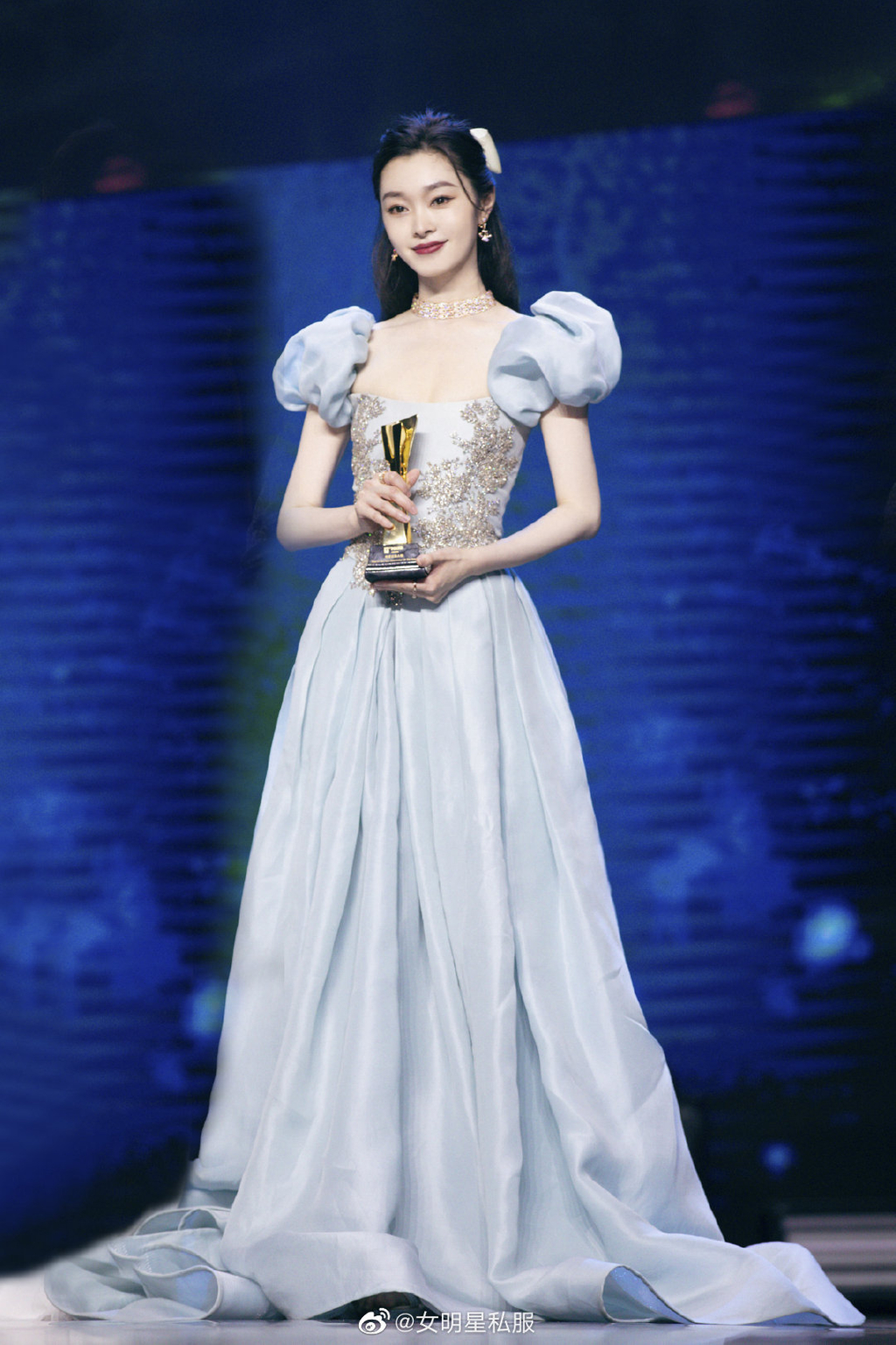 Tống Dật chọn lối trang điểm tập trung vào son đỏ thẫm nổi bật như nàng Bạch Tuyết, tóc buộc nửa nữ tính, đính nơ siêu xinh. Thiết kế phần vai bồng giúp tổng thể vóc dáng hài hòa hơn