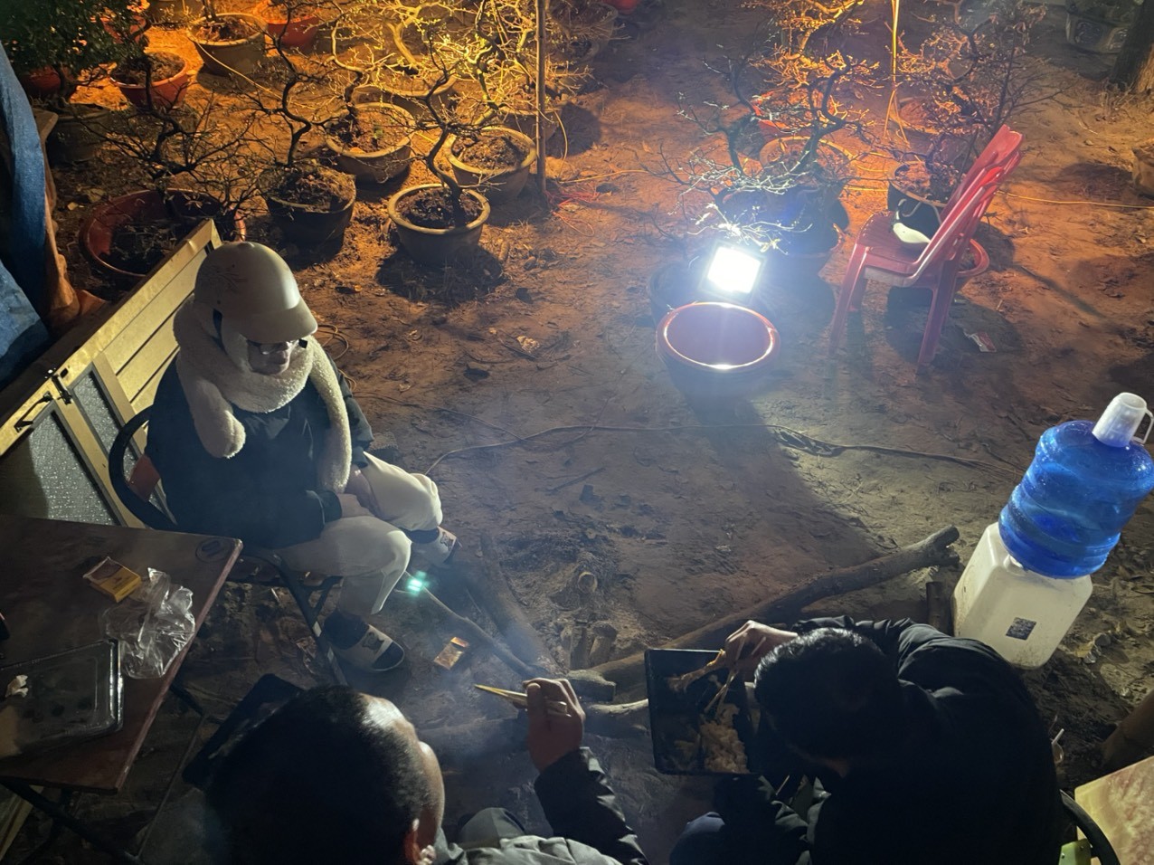 Hàng trăm người buôn bán cây cảnh, hoa... phục vụ Tết ở Tp.Vinh đã phải đốt những đống lửa lớn để sưởi ấm. Cái rét 13°C khiến cho những người bán hoa, cây cảnh này càng thêm vất vả. Bên đường, anh Trần Văn Sơn, trú ở huyện Tương Dương, tỉnh Nghệ An cùng những người thân trong gia đình đang đốt lừa chong đèn để sưởi ấm cho những cây mai của mình. Tranh thủ khi không có khách, anh Sơn gọi mấy suất cơm về cho các anh chị em trong nhà ăn. Theo anh Sơn toàn bộ vốn liếng mình có được đã đầu tư vào buôn mai. 'Năm nay đến ngày 27 Tết mà chúng tôi chưa bán được 1/3 hàng. Toàn bộ vốn liếng đều đầu tư vào đây. Năm nay sức mua kém chúng tôi đang sợ mất Tết. Mấy năm đi buôn hàng hoa tôi chưa từng có khái niệm sắm sang Tết trong nhà. Năm nào bán được hàng sớm thì được về ăn Tết sớm, năm nào ế thì phải đến tận chiều 30 Tết mới về tới nhà', anh Sơn chia sẻ.