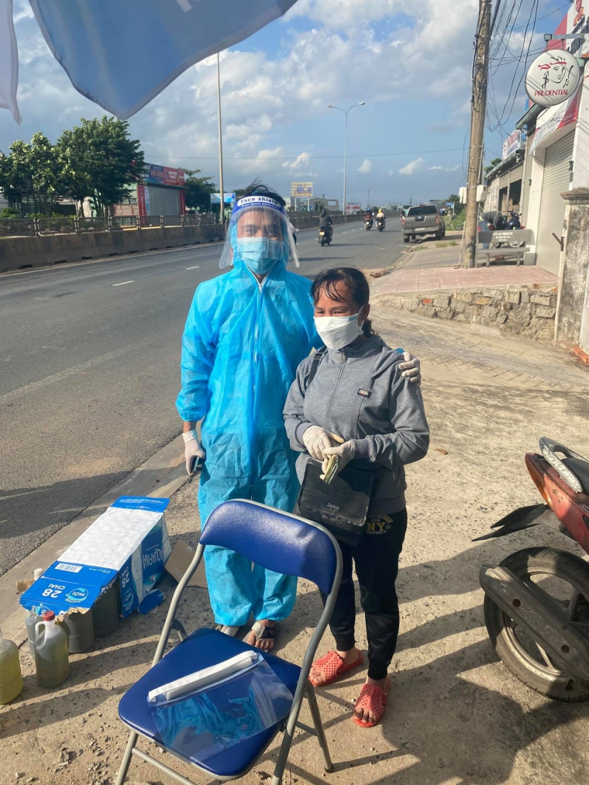 Chị Huệ giản dị cầm xấp tiền phát cho bà con về quê tránh dịch bằng xe máy. Ảnh: FB Chị Huệ giản dị cầm xấp tiền phát cho bà con về quê tránh dịch bằng xe máy. Ảnh: FB