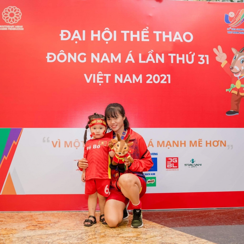 Tuyển thủ Phạm Thị Hoàng Quỳnh bên cạnh tấm HCV SEA Games cùng con gái. Ảnh: Internet Tuyển thủ Phạm Thị Hoàng Quỳnh bên cạnh tấm HCV SEA Games cùng con gái. Ảnh: Internet